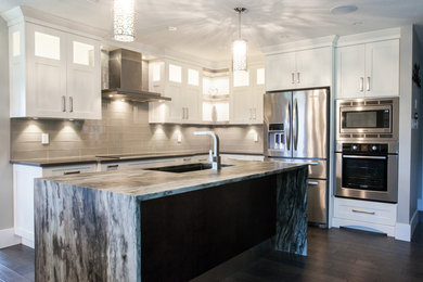 Large traditional u-shaped eat-in kitchen in Toronto with an undermount sink, recessed-panel cabinets, white cabinets, quartz benchtops, grey splashback, glass tile splashback, stainless steel appliances, dark hardwood floors, with island, brown floor and multi-coloured benchtop.