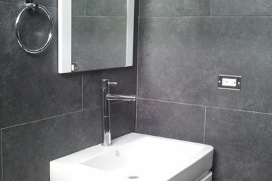 Small trendy 3/4 black tile and porcelain tile porcelain tile and gray floor bathroom photo in Other with flat-panel cabinets, white cabinets, a one-piece toilet, black walls and an integrated sink
