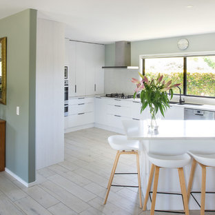 Mittelgroße Skandinavische Küche in U-Form mit Vorratsschrank, Unterbauwaschbecken, flächenbündigen Schrankfronten, weißen Schränken, Quarzwerkstein-Arbeitsplatte, Küchenrückwand in Weiß, Küchengeräten aus Edelstahl, Keramikboden, Kücheninsel, beigem Boden und weißer Arbeitsplatte in Sonstige