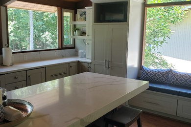 Example of a large transitional u-shaped light wood floor and multicolored floor eat-in kitchen design in Baltimore with an undermount sink, shaker cabinets, white cabinets, quartz countertops, white backsplash, stone slab backsplash, paneled appliances, two islands and white countertops