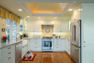 Example of a large classic u-shaped medium tone wood floor open concept kitchen design in Seattle with a farmhouse sink, recessed-panel cabinets, white cabinets, granite countertops, yellow backsplash, stainless steel appliances, no island and stone tile backsplash