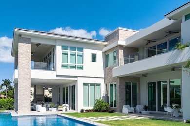 Example of a large transitional white two-story stucco house exterior design in Miami with a hip roof and a tile roof