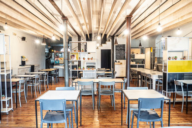 Esempio di una sala da pranzo aperta verso il soggiorno industriale di medie dimensioni con pareti multicolore, pavimento in legno verniciato, nessun camino e pavimento marrone