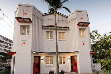 Photo of a traditional three-storey stucco beige duplex exterior in Brisbane with a gable roof and a metal roof.