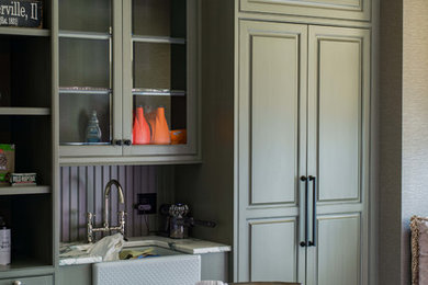 Utility room - large traditional single-wall porcelain tile utility room idea in Chicago with a farmhouse sink, raised-panel cabinets, granite countertops, green cabinets and beige walls