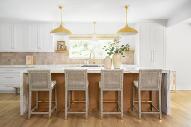 Large minimalist l-shaped light wood floor and beige floor eat-in kitchen photo in Los Angeles with shaker cabinets, white cabinets, an island, quartz countertops, brown backsplash, cement tile backsplash, beige countertops, white appliances and a farmhouse sink