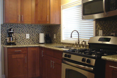Photo of a mid-sized transitional l-shaped eat-in kitchen in Los Angeles with a double-bowl sink, shaker cabinets, medium wood cabinets, granite benchtops, multi-coloured splashback, mosaic tile splashback, stainless steel appliances, cement tiles, no island, beige floor and brown benchtop.