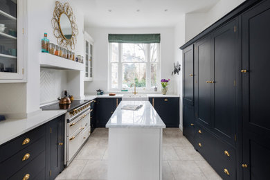 Traditional u-shaped enclosed kitchen in London with a belfast sink, shaker cabinets, black cabinets, marble worktops, white splashback, integrated appliances, an island, beige floors and multicoloured worktops.