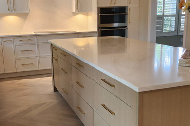 Example of a large transitional light wood floor and beige floor eat-in kitchen design in Other with a farmhouse sink, shaker cabinets, white cabinets, quartzite countertops, white backsplash, quartz backsplash, stainless steel appliances, an island and white countertops