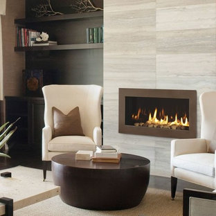 Foto di un piccolo soggiorno minimal chiuso con pareti beige, pavimento in gres porcellanato, camino classico, cornice del camino in pietra e nessuna TV
