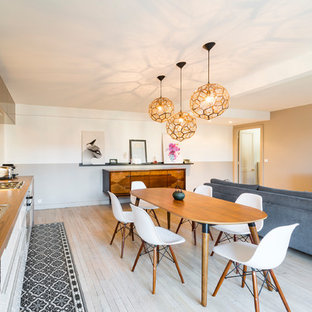 Exemple d'une salle à manger ouverte sur le salon tendance avec un mur blanc, un sol en bois clair, aucune cheminée et un sol beige.