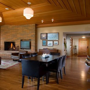 Design ideas for a large contemporary open plan dining in Minneapolis with a brick fireplace surround, beige walls, light hardwood floors and a corner fireplace.