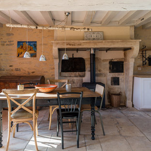 ディジョンの中サイズのカントリー風 LDKの画像 (ベージュの壁、薪ストーブ、石材の暖炉まわり、ベージュの床)