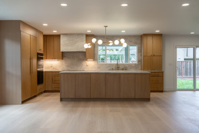 Example of a mid-sized l-shaped light wood floor eat-in kitchen design in San Francisco with a drop-in sink, shaker cabinets, medium tone wood cabinets, quartzite countertops, beige backsplash, stone slab backsplash, black appliances, an island and beige countertops