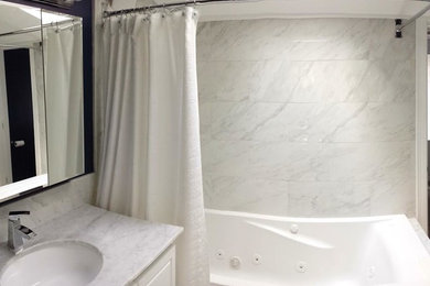 Mid-sized trendy 3/4 gray tile and white tile tub/shower combo photo in Boston with raised-panel cabinets, white cabinets, white walls, an undermount sink and marble countertops