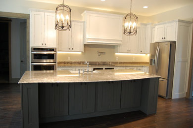 Mountain style dark wood floor kitchen photo in Other with a farmhouse sink, shaker cabinets, granite countertops, gray backsplash, stainless steel appliances and an island