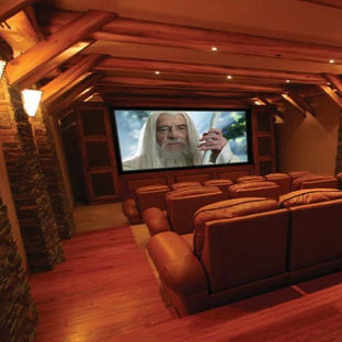 Large rustic open plan home cinema in Detroit with black walls, painted wood flooring and a wall mounted tv.