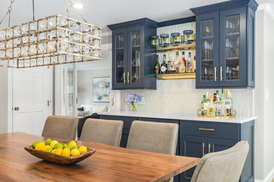 Design ideas for a mid-sized contemporary u-shaped eat-in kitchen in Boston with a farmhouse sink, recessed-panel cabinets, white cabinets, quartz benchtops, grey splashback, ceramic splashback, stainless steel appliances and white benchtop.