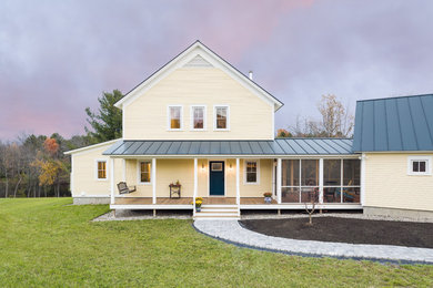 Country yellow two-story wood exterior home photo in Burlington with a metal roof