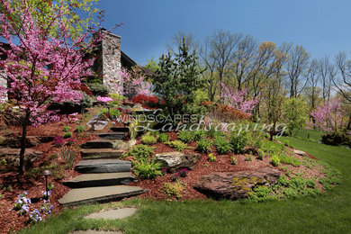Immagine di un giardino esposto in pieno sole in primavera con pavimentazioni in pietra naturale