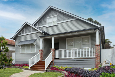 This is an example of a large traditional two-storey grey house exterior in Melbourne with a gable roof, a metal roof, a grey roof and wood siding.