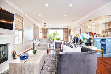 Living room - mid-sized transitional open concept medium tone wood floor and brown floor living room idea in Los Angeles with beige walls, a standard fireplace and a wall-mounted tv