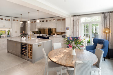 Cette photo montre une grande cuisine chic avec un placard à porte shaker, des portes de placard blanches, un plan de travail en granite, une crédence miroir, îlot et un plan de travail blanc.