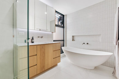 Design ideas for a large contemporary master bathroom in Sydney with flat-panel cabinets, medium wood cabinets, a freestanding tub, an open shower, a wall-mount toilet, ceramic tile, white walls, an undermount sink, engineered quartz benchtops, a hinged shower door, white benchtops, a single vanity and a freestanding vanity.
