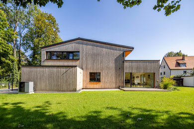 Zweistöckiges Modernes Haus mit grauer Fassadenfarbe, Satteldach, Ziegeldach, grauem Dach und Verschalung in München