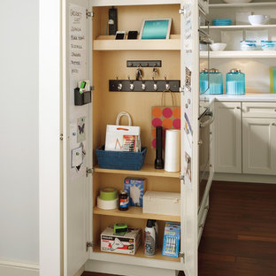 Idée de décoration pour une arrière-cuisine tradition en L avec un sol en bois brun, un plan de travail blanc, un placard avec porte à panneau encastré, des portes de placard beiges et une crédence blanche.