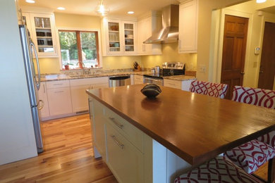 Inspiration for a mid-sized transitional u-shaped medium tone wood floor and brown floor eat-in kitchen remodel with a double-bowl sink, shaker cabinets, white cabinets, granite countertops, stainless steel appliances and an island