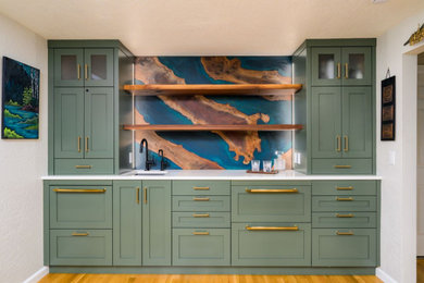 Example of a large transitional u-shaped medium tone wood floor and brown floor wet bar design in Portland with an integrated sink, recessed-panel cabinets, green cabinets, quartz countertops, multicolored backsplash and white countertops
