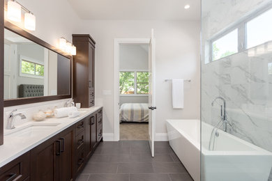 Design ideas for a mid-sized contemporary master bathroom in Houston with a freestanding tub, a corner shower, grey walls, porcelain floors, an undermount sink, grey floor, a hinged shower door, shaker cabinets, dark wood cabinets, gray tile, white tile, marble and solid surface benchtops.