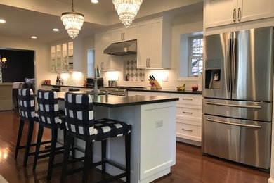 This is an example of a kitchen in DC Metro with a farmhouse sink, shaker cabinets, white cabinets, granite benchtops, white splashback, subway tile splashback, stainless steel appliances, medium hardwood floors, with island and brown floor.