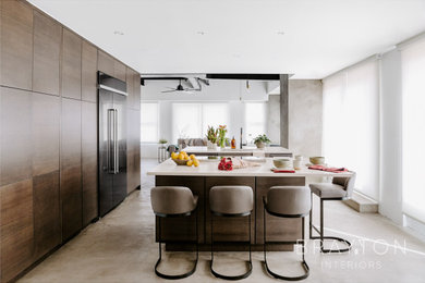 Eat-in kitchen - industrial concrete floor, gray floor and exposed beam eat-in kitchen idea in Denver with flat-panel cabinets, dark wood cabinets, quartz countertops, mirror backsplash, stainless steel appliances, two islands and beige countertops