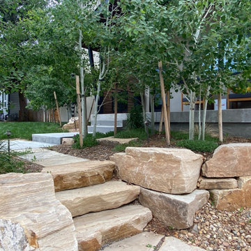 Mountain inspired minimalist boulder retaining walls and plantings.