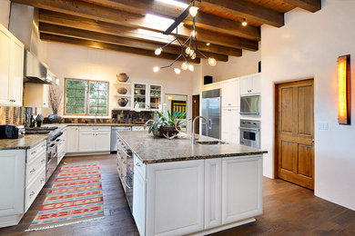 Inspiration for a large southwestern l-shaped dark wood floor kitchen remodel in Albuquerque with an undermount sink, shaker cabinets, white cabinets, granite countertops, multicolored backsplash, mosaic tile backsplash, stainless steel appliances and an island