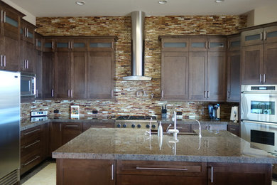 Open concept kitchen - mid-sized contemporary open concept kitchen idea in Phoenix with a farmhouse sink, shaker cabinets, medium tone wood cabinets, granite countertops, brown backsplash, stainless steel appliances and two islands