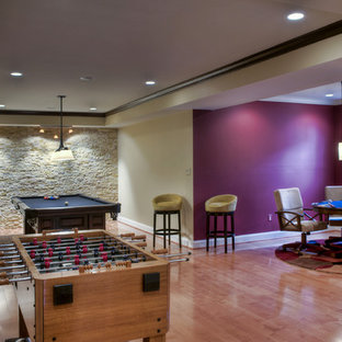 This is an example of a medium sized contemporary walk-out basement in DC Metro with pink walls and medium hardwood flooring.