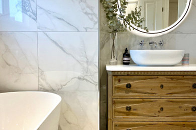 Inspiration for a medium sized bohemian family bathroom in Berkshire with shaker cabinets, light wood cabinets, a freestanding bath, a corner shower, a wall mounted toilet, grey tiles, porcelain tiles, porcelain flooring, a console sink, quartz worktops, grey floors, a hinged door, white worktops, a single sink and a freestanding vanity unit.