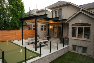 Example of a mid-sized minimalist backyard concrete paver patio design in Toronto with a bbq area and a roof extension