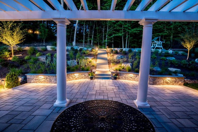 Photo of a large traditional backyard patio in New York with an outdoor kitchen, natural stone pavers and a pergola.