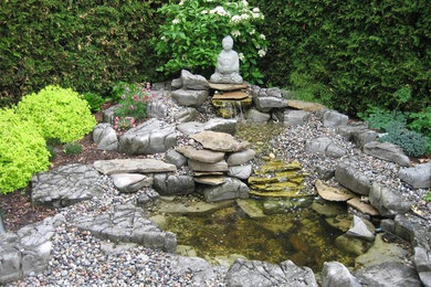 Design ideas for a mid-sized traditional backyard garden in Toronto with a water feature and concrete pavers.