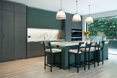 Design ideas for a medium sized contemporary single-wall kitchen/diner in Kent with flat-panel cabinets, medium wood cabinets, quartz worktops, white splashback, stainless steel appliances, an island and white worktops.