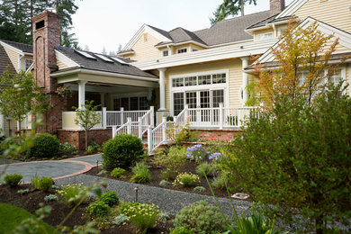 This is an example of a large traditional two-storey yellow exterior in Seattle with vinyl siding and a gable roof.