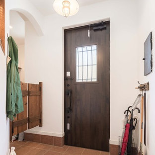 東京都下の片開きドアアジアンスタイルのおしゃれなマッドルーム (白い壁、濃色木目調のドア、茶色い床) の写真