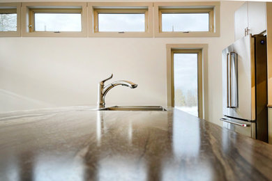 Open concept kitchen - mid-sized traditional single-wall laminate floor, gray floor and vaulted ceiling open concept kitchen idea in Vancouver with a double-bowl sink, flat-panel cabinets, beige cabinets, laminate countertops, brown backsplash, ceramic backsplash, stainless steel appliances, an island and multicolored countertops