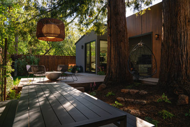 Идея дизайна: маленький участок и сад на заднем дворе в стиле модернизм с местом для костра, полуденной тенью, настилом и с деревянным забором для на участке и в саду