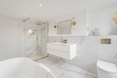 Contemporary bathroom in London with flat-panel cabinets, white cabinets, a freestanding bath, a walk-in shower, a wall mounted toilet, white tiles, ceramic tiles, white walls, ceramic flooring, a wall-mounted sink, engineered stone worktops, white floors, an open shower, white worktops, a single sink and a floating vanity unit.