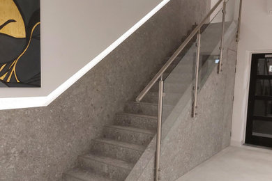 ハートフォードシャーにある高級な中くらいなモダンスタイルのおしゃれな階段 (タイルの蹴込み板、金属の手すり、パネル壁) の写真